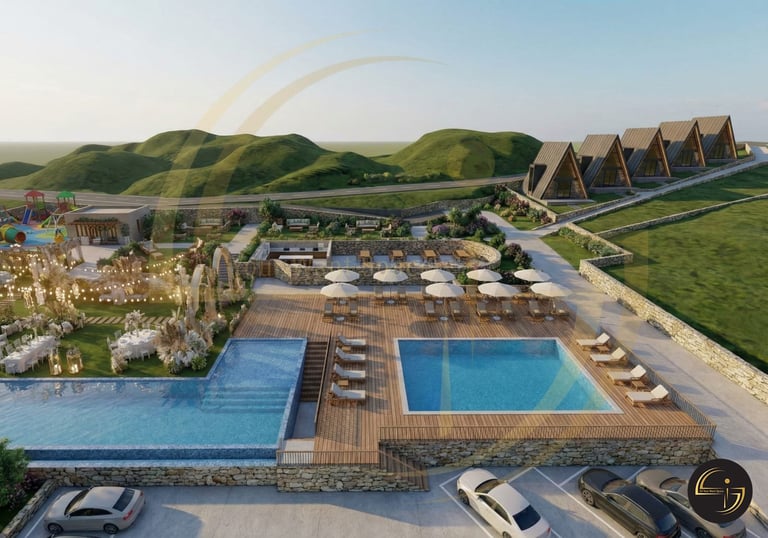 Aerial view of a luxury resort with two swimming pools, wooden decking, modern lodge buildings, and green rolling hills in the background