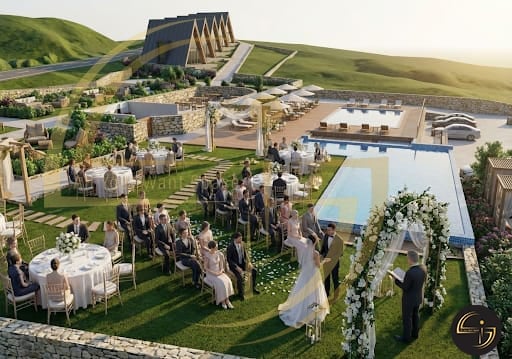 Aerial view of outdoor wedding ceremony on manicured lawn with guests, floral arch, and modern architecture buildings in background